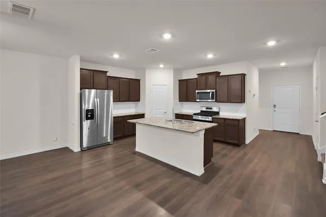 a kitchen with stainless steel appliances granite countertop a refrigerator stove top oven and cabinets