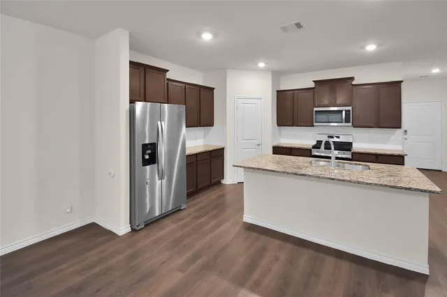a kitchen with stainless steel appliances granite countertop a refrigerator and a stove top oven