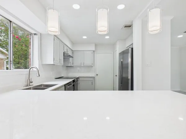 a kitchen with stainless steel appliances kitchen island a sink a refrigerator and a window