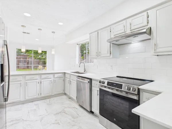 a kitchen with granite countertop a stove sink and cabinets