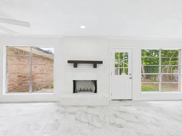 an empty room with windows and fireplace