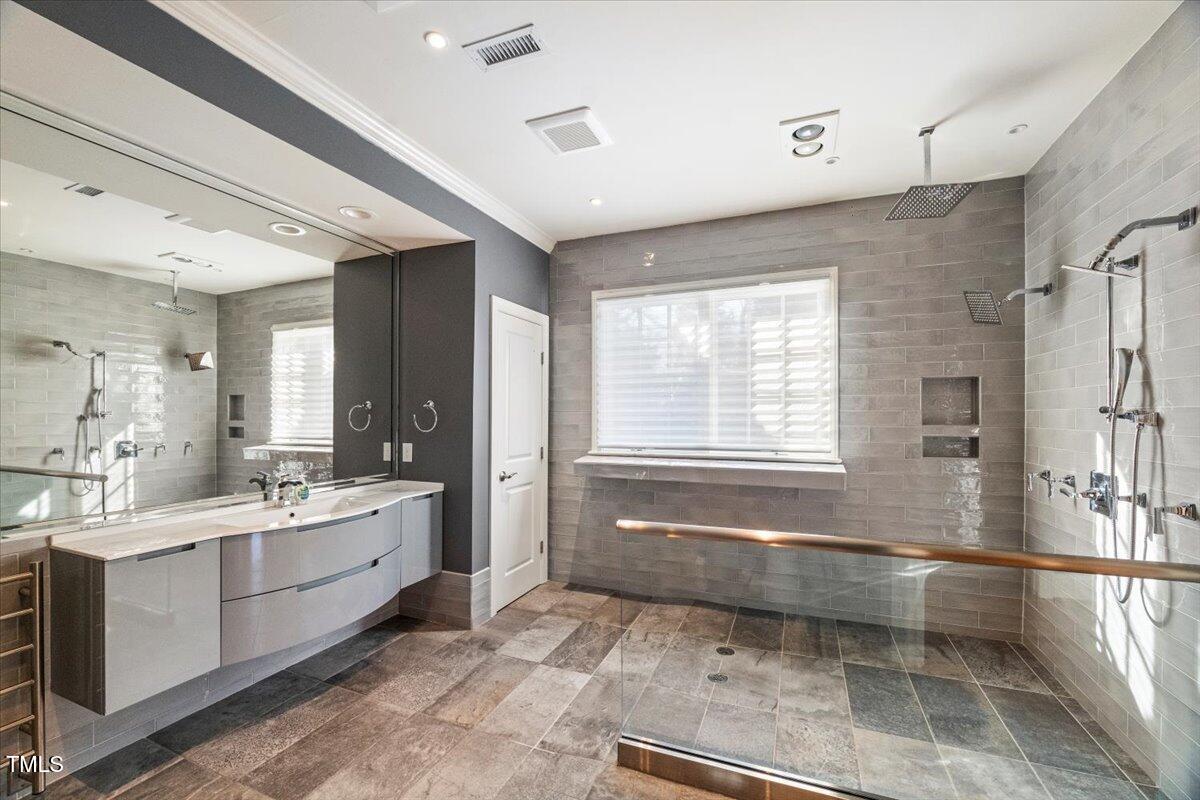 255 Penley Circle Raleigh, NC 27609 - Photo 21 of 35 a bathroom with a double vanity sink large mirror and a bathtub