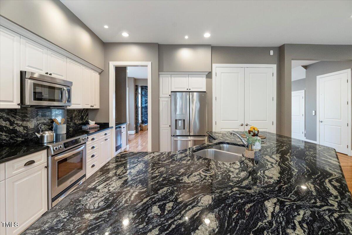 255 Penley Circle Raleigh, NC 27609 - Photo 6 of 35 a large kitchen with kitchen island granite countertop a stove a sink and a microwave