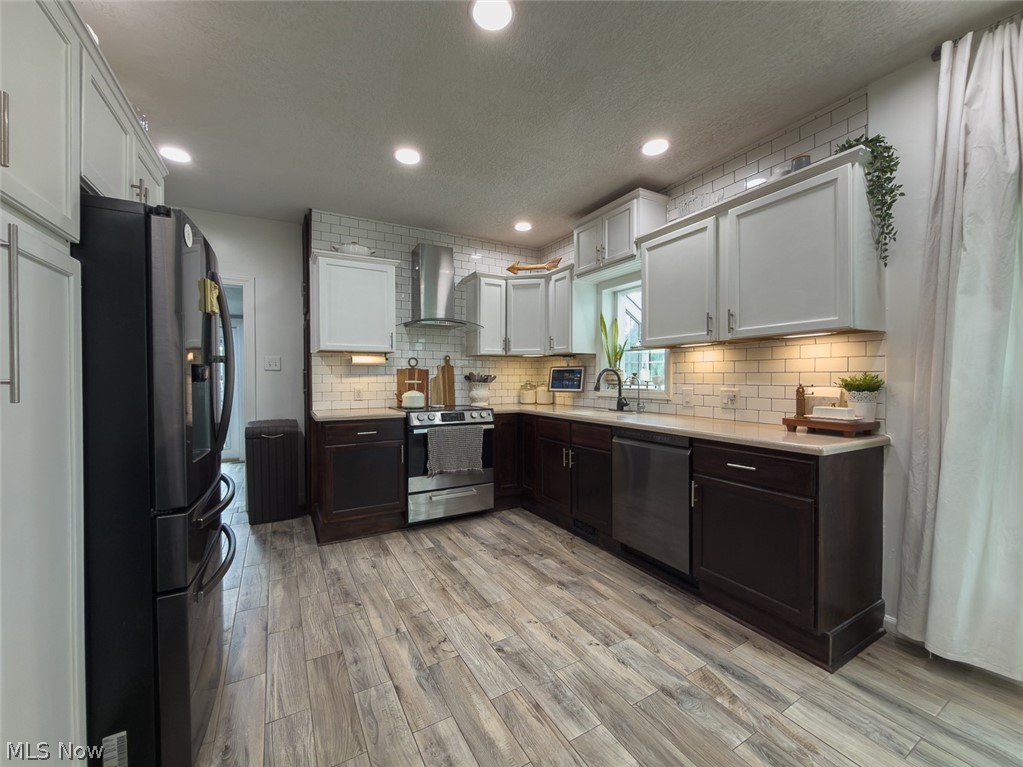 13429 West Calla Road Salem, OH 44460 - Photo 4 of 27 Modern kitchen featuring wood-finish flooring, two-tone cabinetry, subway tile backsplash, recessed lighting, and stainless steel appliances
