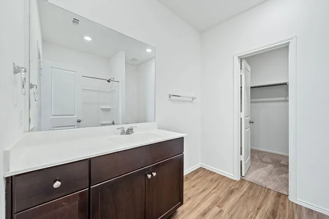 a view of a sink a mirror and wooden cabinets