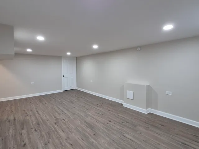 a view of an empty room with wooden floor and closet
