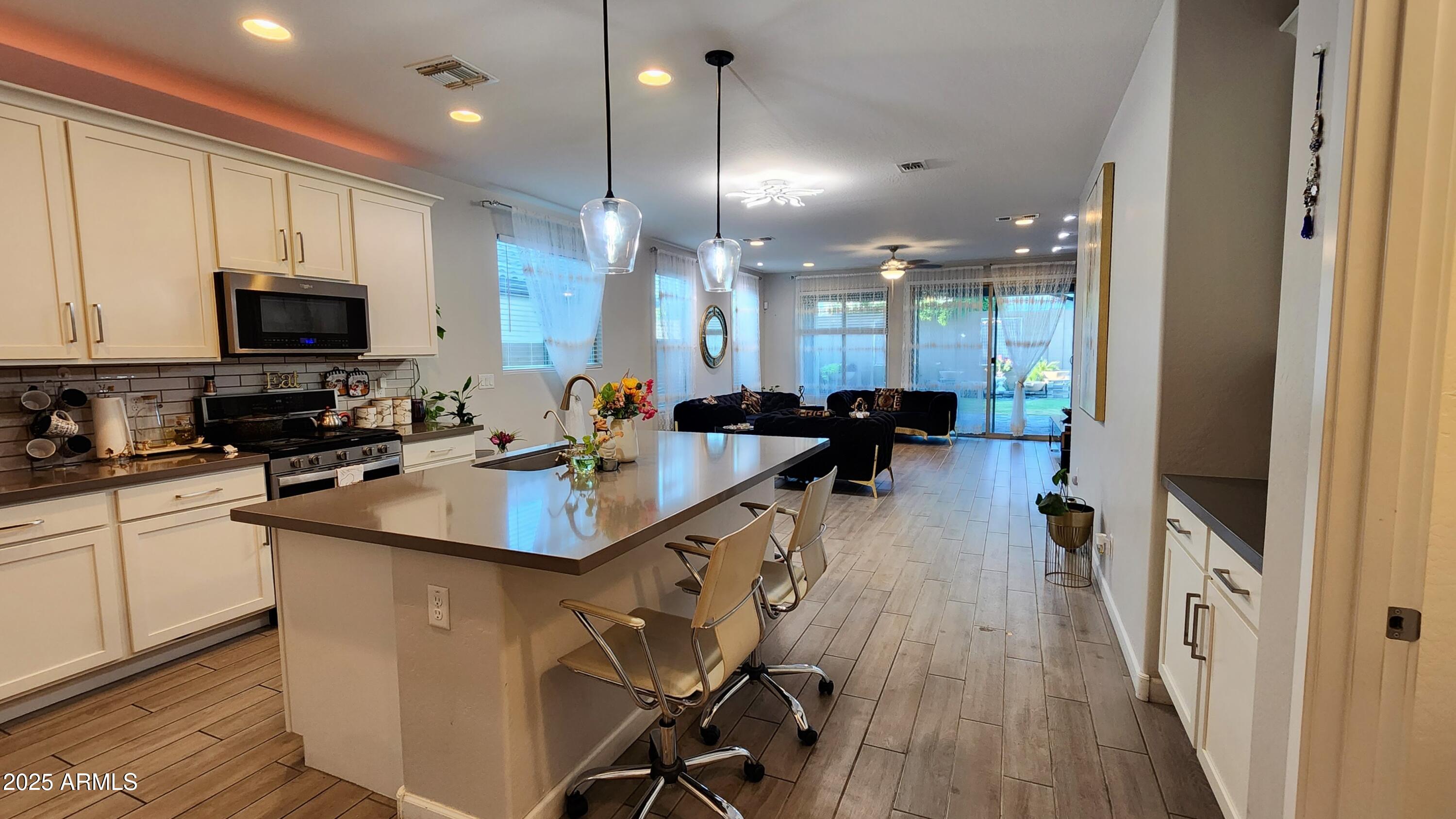 14400 West Bloomfield Road Surprise, AZ 85379 - Photo 5 of 38 a kitchen with stainless steel appliances a sink a stove a refrigerator cabinets and living room view