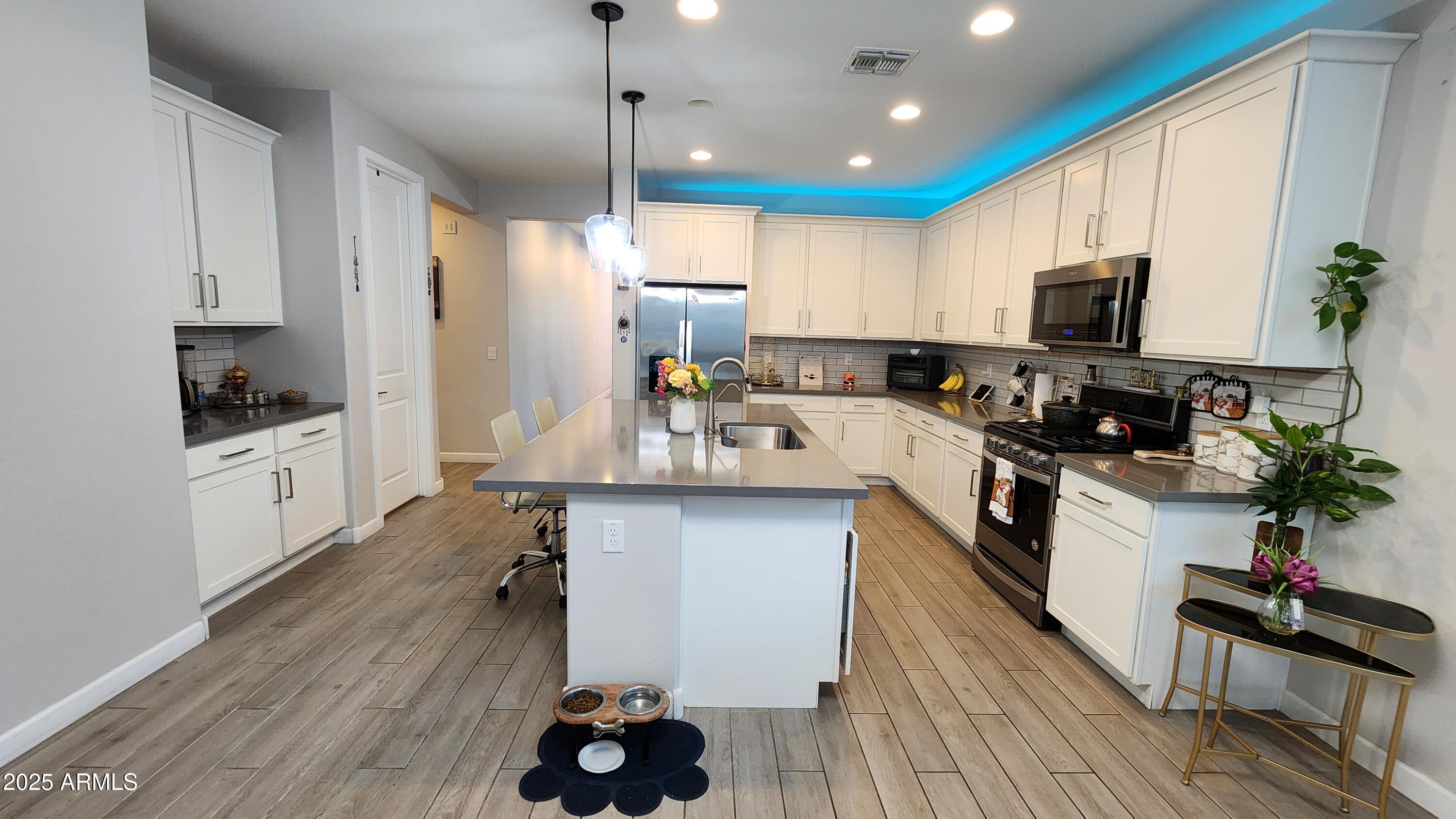 14400 West Bloomfield Road Surprise, AZ 85379 - Photo 7 of 38 a kitchen with stainless steel appliances kitchen island granite countertop a stove a sink a refrigerator and a microwave