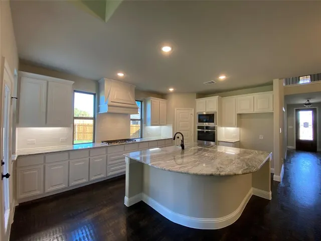 a large kitchen with stainless steel appliances granite countertop a sink a stove and a refrigerator