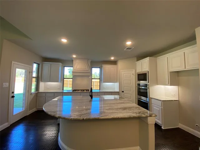 a kitchen with kitchen island a sink stainless steel appliances and a counter top space