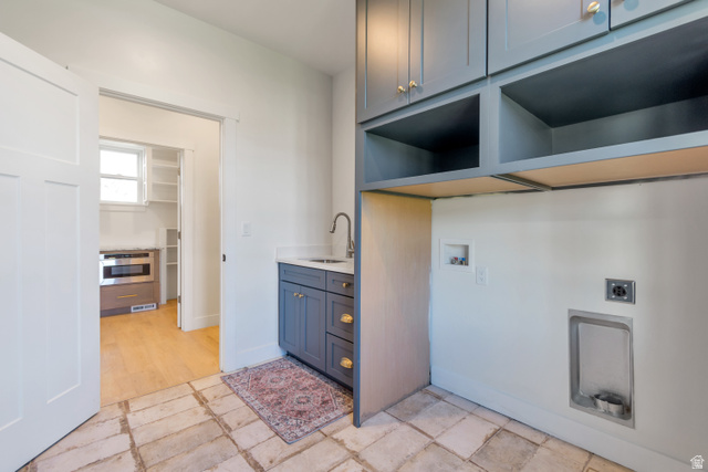 1820 West Farmhouse Flats Road Peoa, UT 84061 - Photo 20 of 79 Dedicated laundry area featuring slate blue cabinetry with gold-tone hardware, a sink with a gooseneck faucet, and built-in shelving