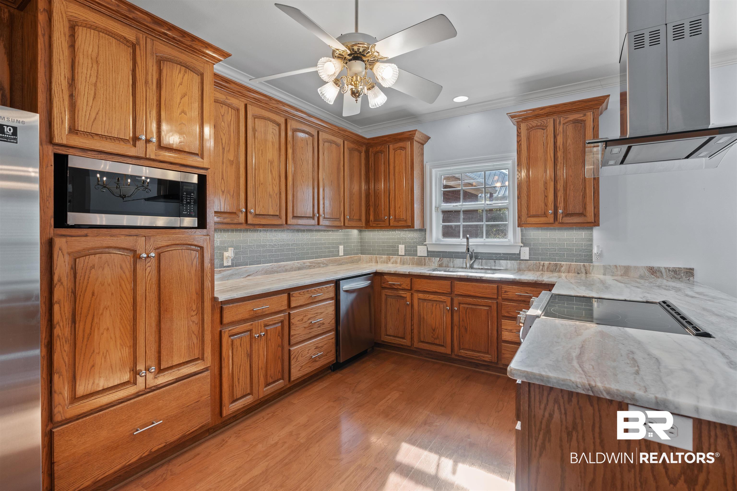 4 Judd Trail Daphne, AL 36527 - Photo 9 of 45 Kitchen featuring ventilation hood, brown cabinetry, a sink, light wood-style floors, and appliances with stainless steel finishes
