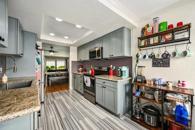 a kitchen with granite countertop lots of clutter and stainless steel appliances
