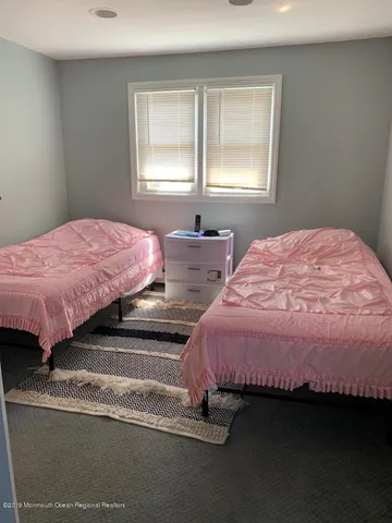 a bedroom with two beds and next to a window