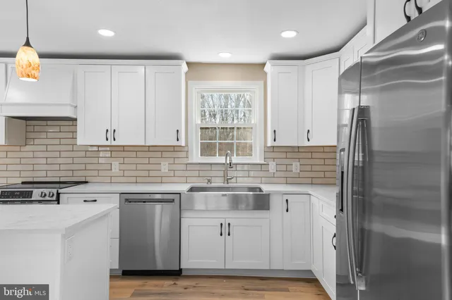 a kitchen with stainless steel appliances granite countertop a sink a stove and a wooden floors