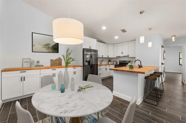 a kitchen with a dining table chairs and refrigerator