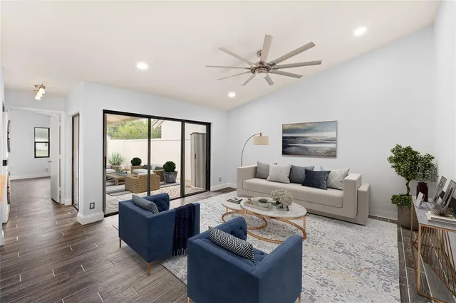 a living room with furniture floor to ceiling window and a flat screen tv