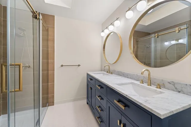 a bathroom with a granite countertop double vanity and a mirror