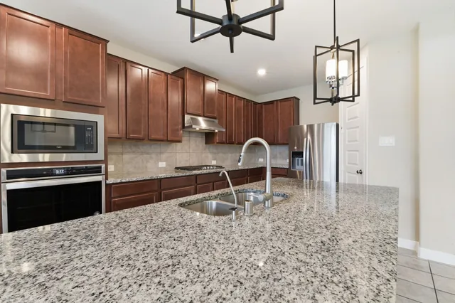 a kitchen with stainless steel appliances granite countertop a stove a sink and a microwave