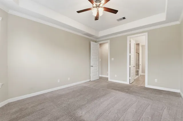 an empty room with a chandelier fan and windows