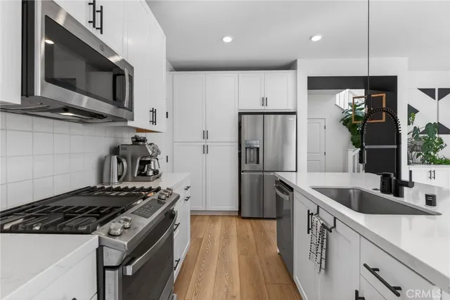 a kitchen with stainless steel appliances granite countertop a sink a stove and a wooden floors
