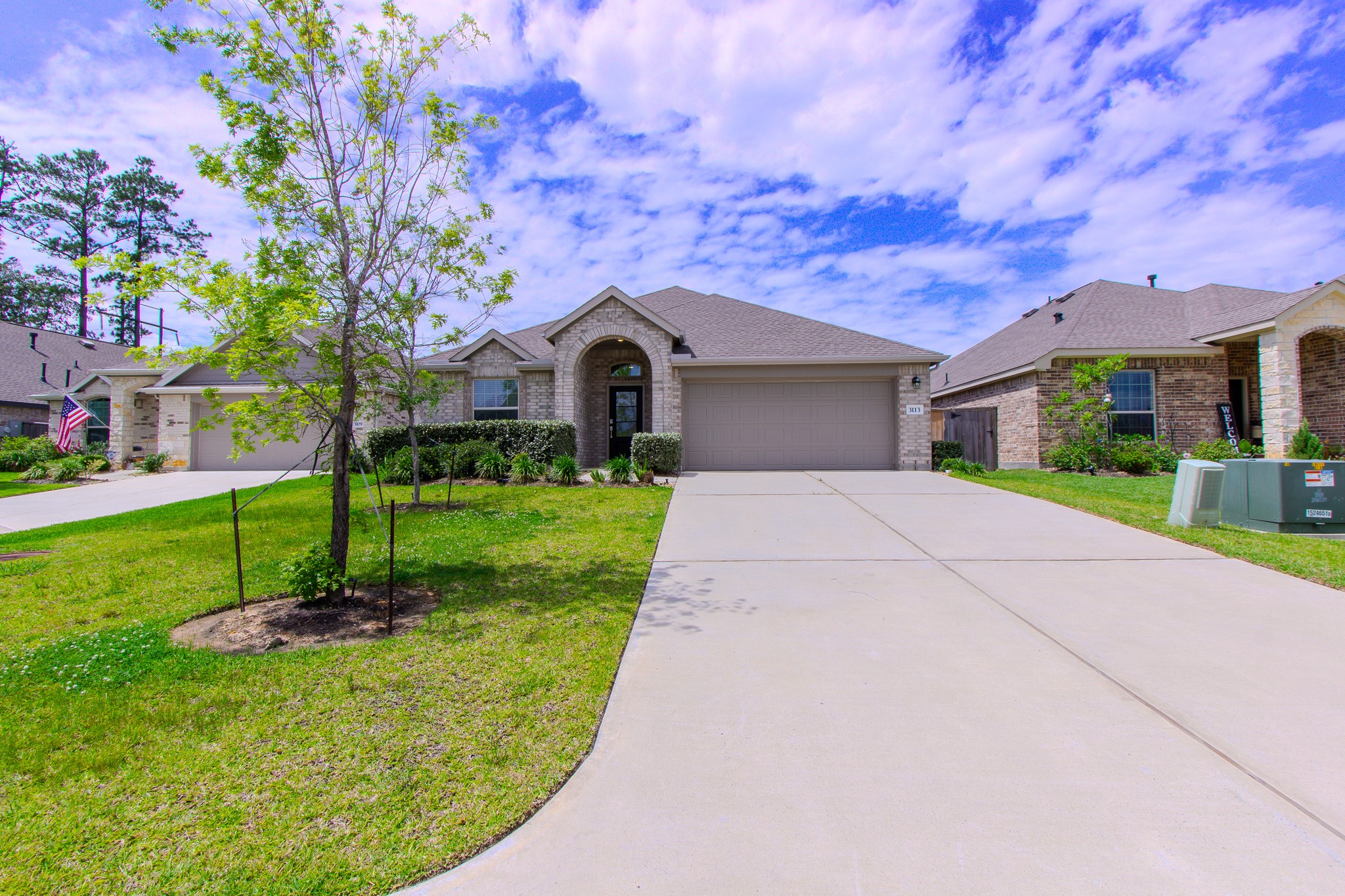 3113 Catalonion Court Conroe, TX 77301 - Photo 3 of 45 a front view of a house with a yard garage and outdoor seating