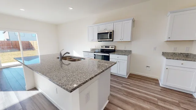 a kitchen with stainless steel appliances granite countertop a sink dishwasher and a stove with wooden floor