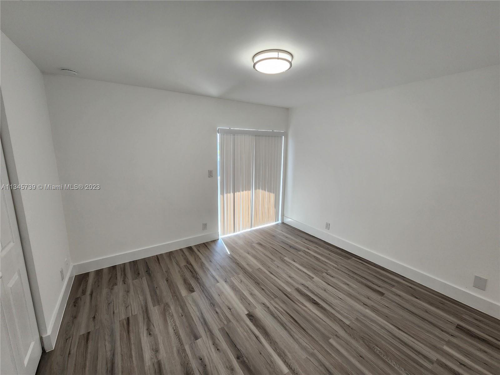 11603 Timbers Way Boca Raton, FL 33428 - Photo 15 of 48 a view of an empty room with wooden floor and a window