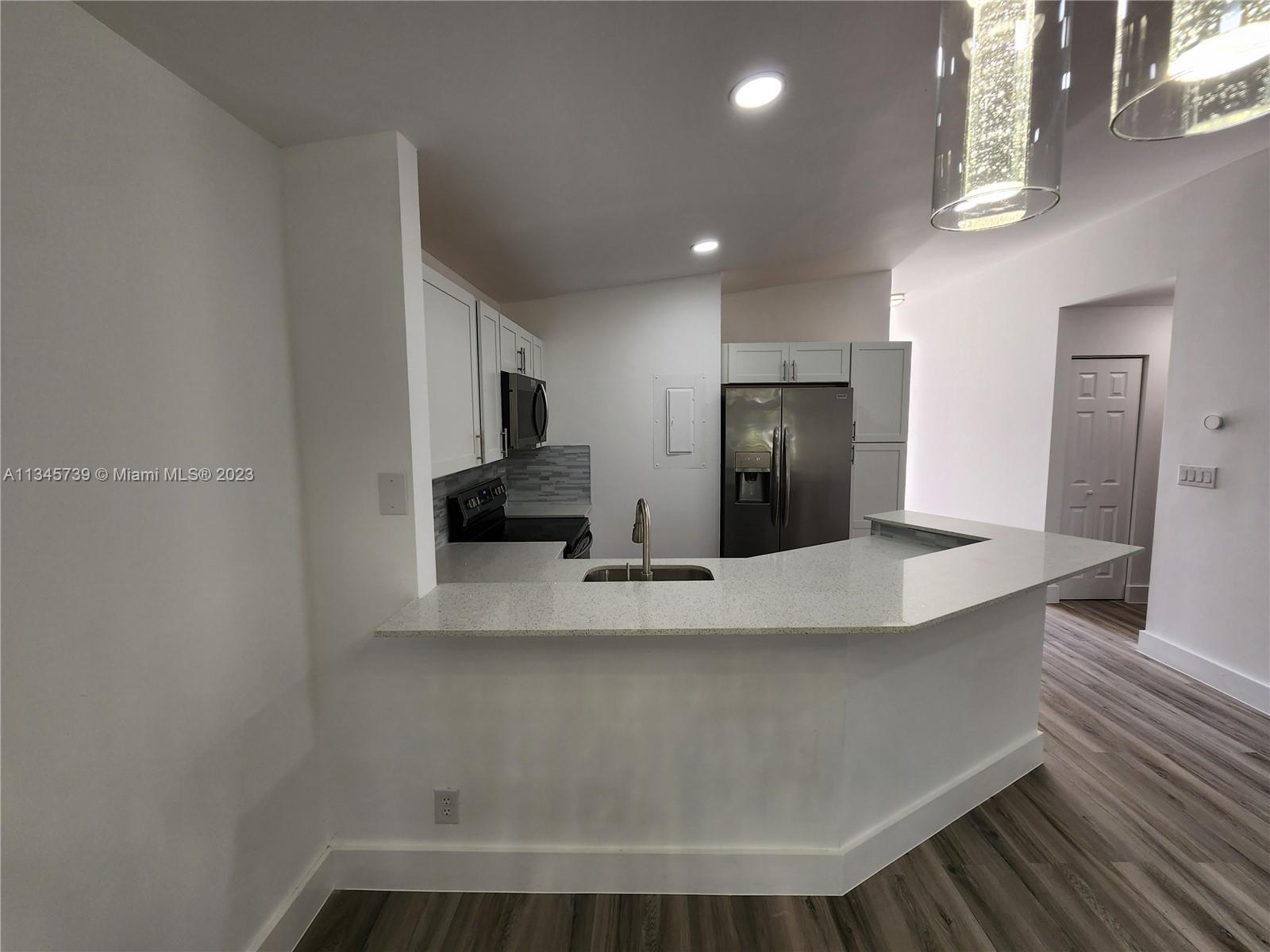 11603 Timbers Way Boca Raton, FL 33428 - Photo 3 of 48 a view of kitchen with stainless steel appliances wooden floor and living room