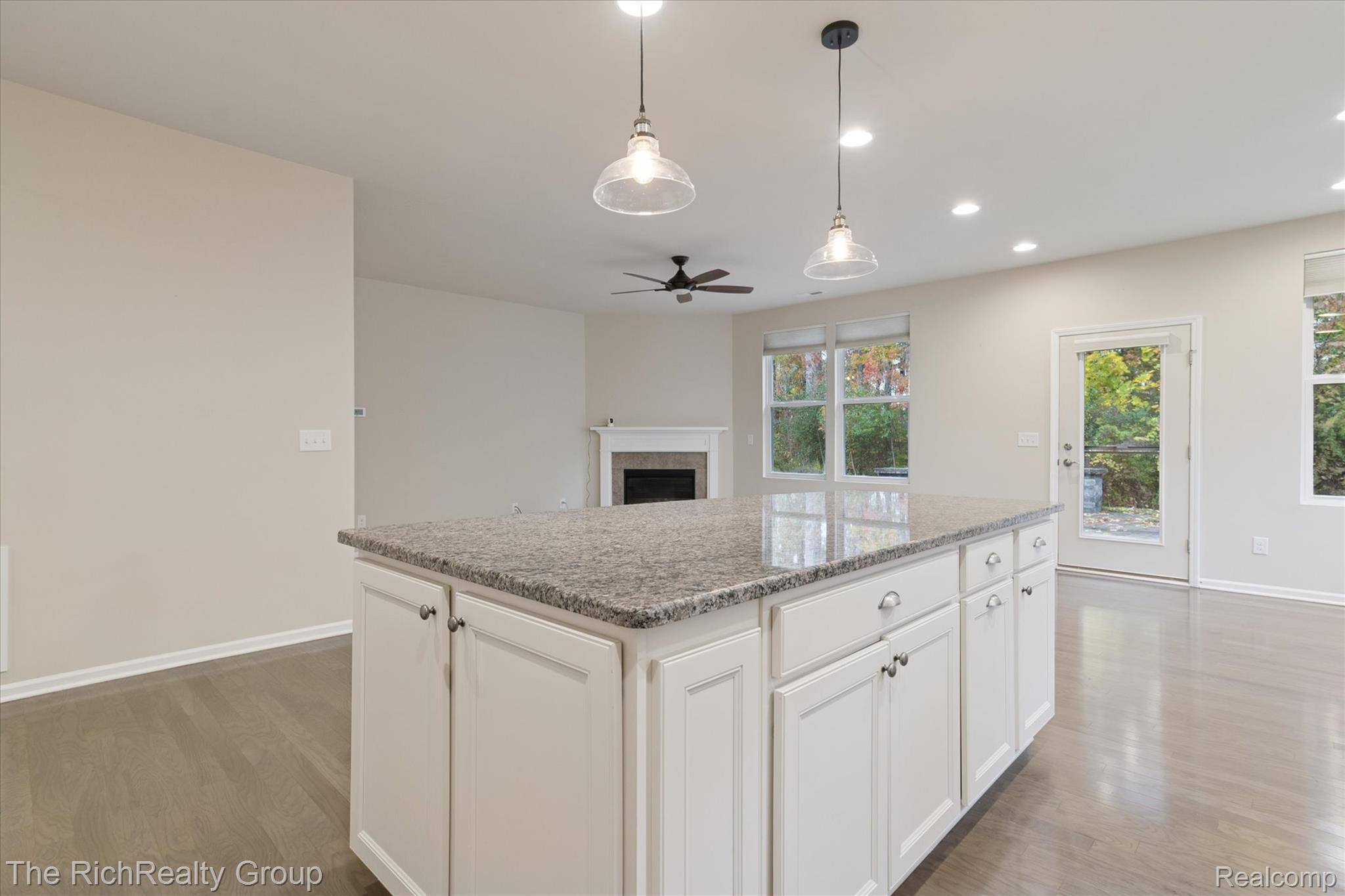 49534 Mapleton Road Canton, MI 48188 - Photo 16 of 37 Kitchen featuring white cabinets, a fireplace, hanging light fixtures, light stone counters, and recessed lighting
