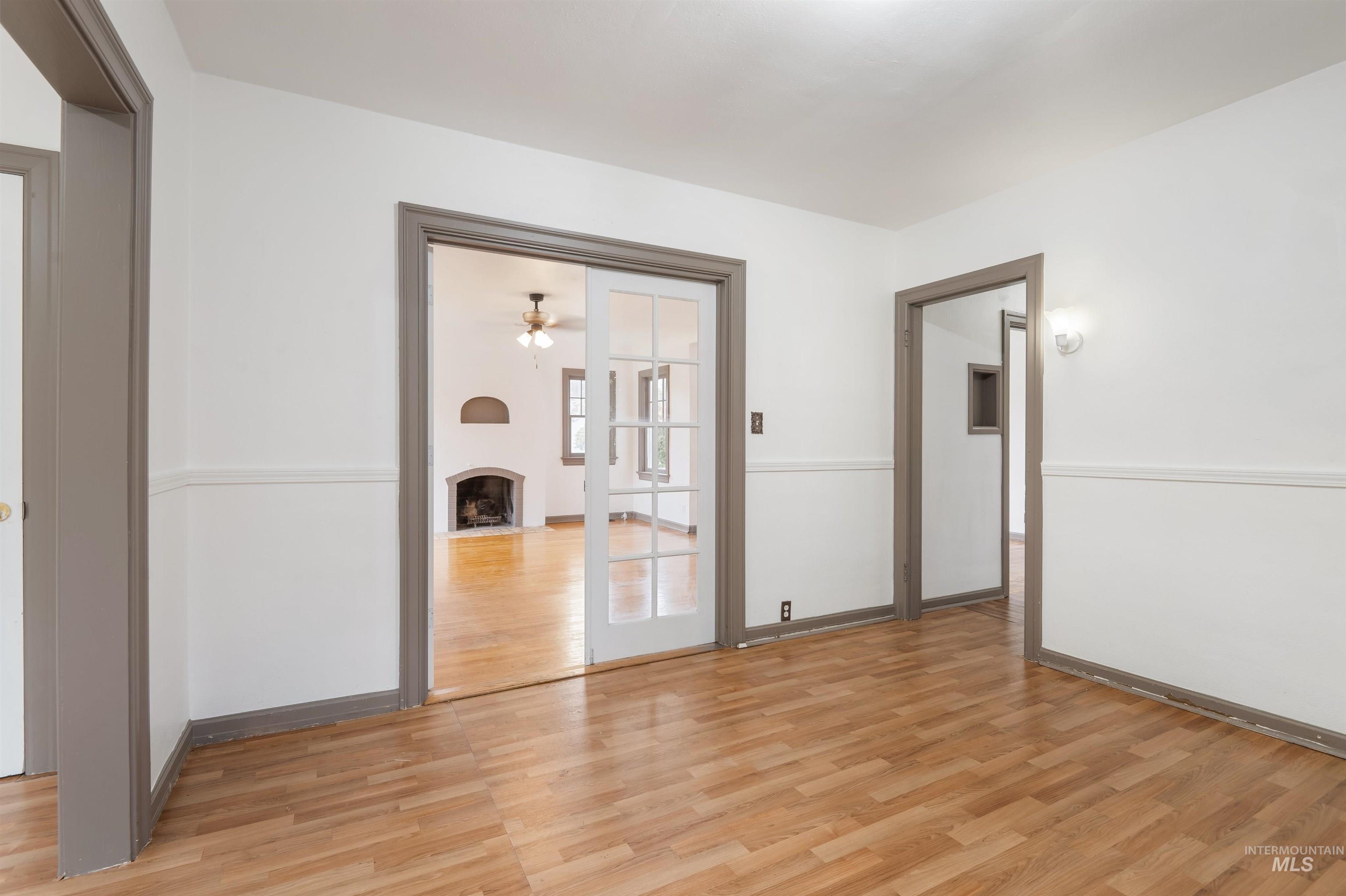 191 Southwest 5th Avenue Ontario, OR 97914 - Photo 12 of 50 Empty room with a large fireplace, light wood-style flooring, and a ceiling fan