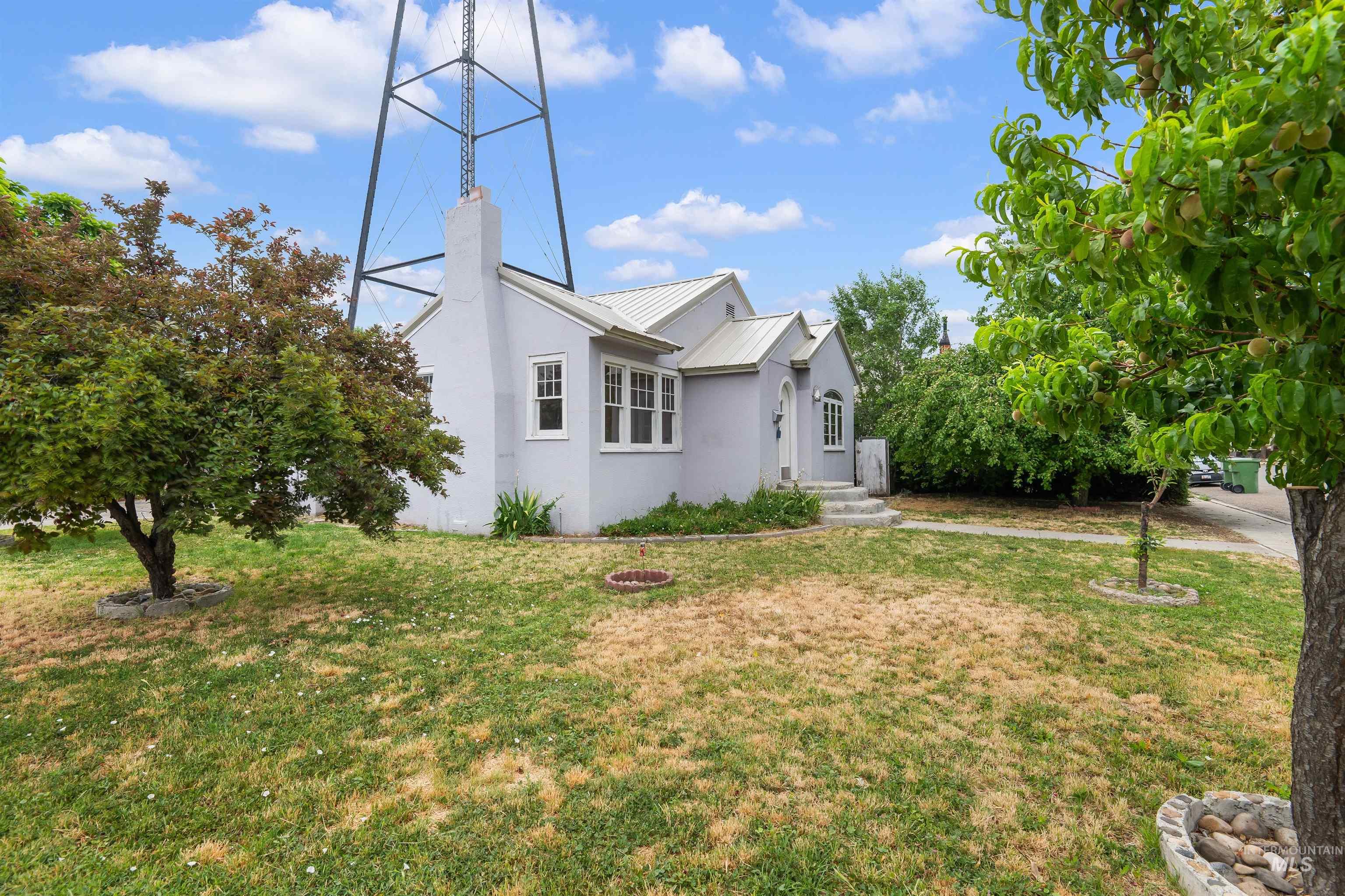 191 Southwest 5th Avenue Ontario, OR 97914 - Photo 3 of 50 View of property exterior featuring stucco siding, a yard, a metal roof, and a chimney