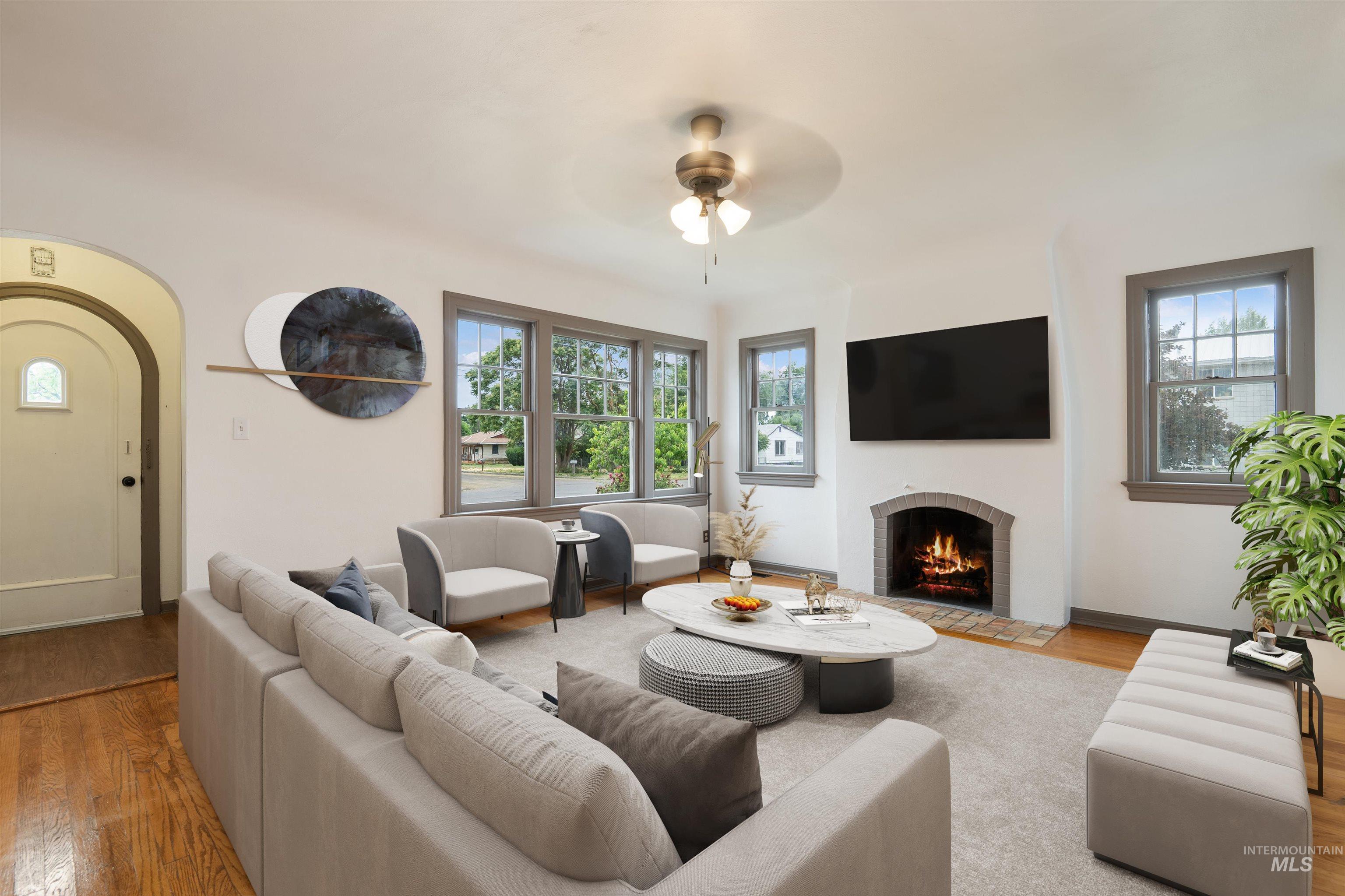 191 Southwest 5th Avenue Ontario, OR 97914 - Photo 48 of 50 Living area featuring arched walkways, a fireplace with flush hearth, ceiling fan, and wood finished floors
