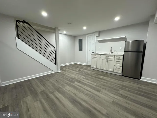 an empty room with wooden floor cabinet and windows