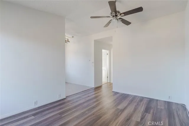 a view of an empty room with a ceiling fan and wooden floor