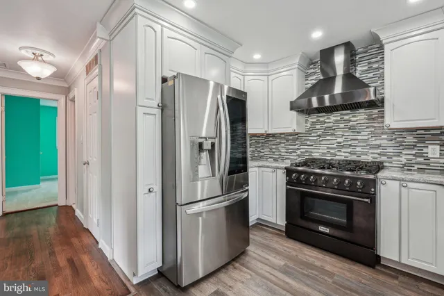 a kitchen with stainless steel appliances a refrigerator and a hard wood floor