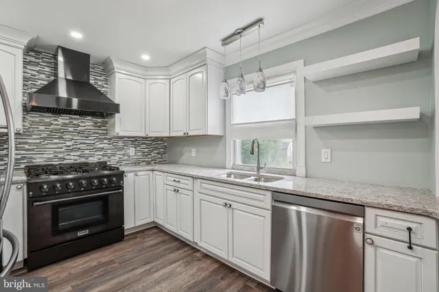 a kitchen with stainless steel appliances granite countertop a stove and white cabinets