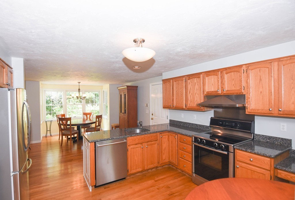 9 Nehemiah Road Shirley, MA 01464 - Photo 2 of 23 a kitchen with granite countertop a stove top oven a sink dishwasher a dining table and chairs with wooden floor