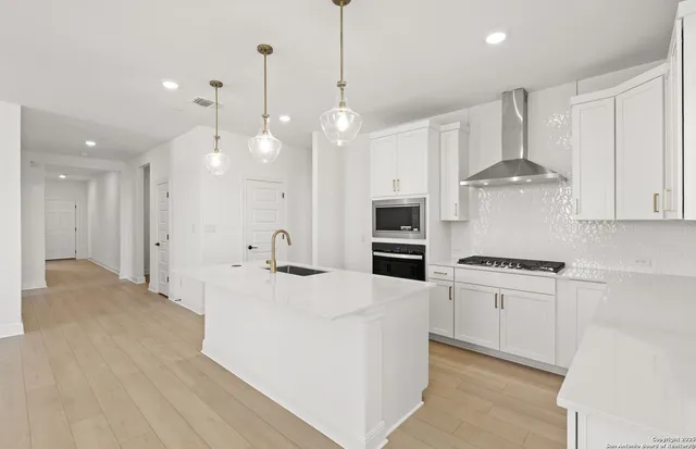 a kitchen with stainless steel appliances a stove a sink a refrigerator and white cabinets