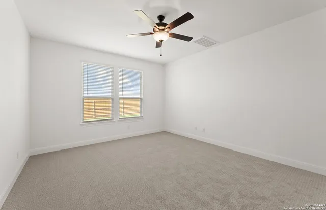 an empty room with ceiling fan and window