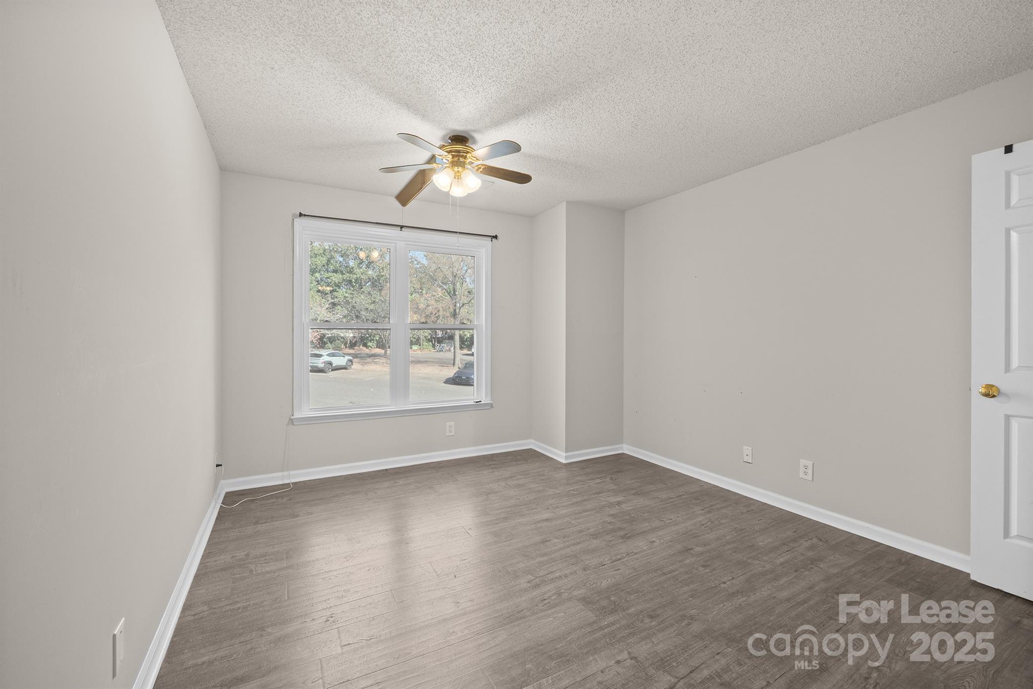 18809 Nautical Drive, Unit 202 Cornelius, NC 28031 - Photo 14 of 32 an empty room with wooden floor chandelier fan and windows