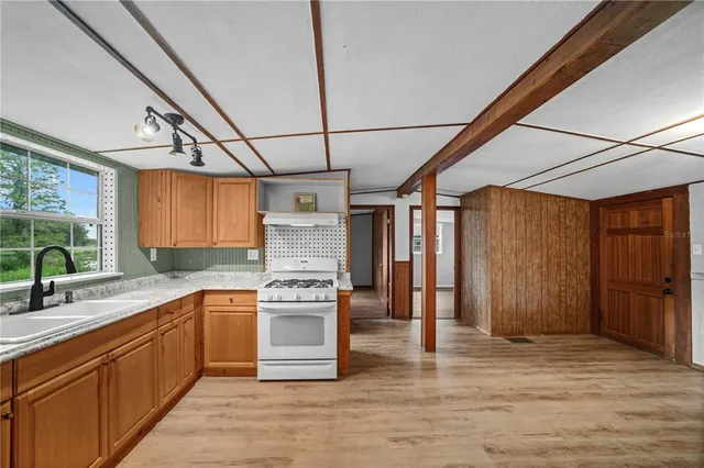 a kitchen with stainless steel appliances granite countertop a sink a stove cabinets counter space and a window