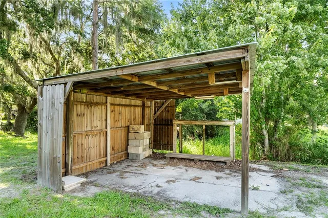 a backyard of a house with lawn chairs plants and large tree