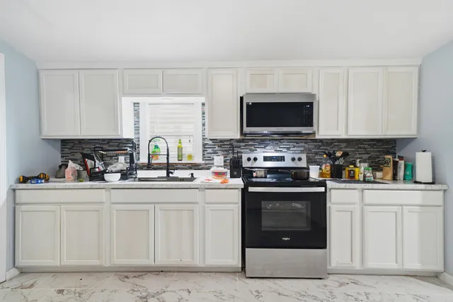 a kitchen with stainless steel appliances granite countertop a stove a sink and a microwave