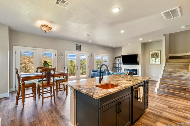 a kitchen with stainless steel appliances granite countertop a table chairs and a refrigerator