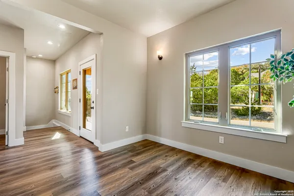 a view of an empty room with wooden floor and a window