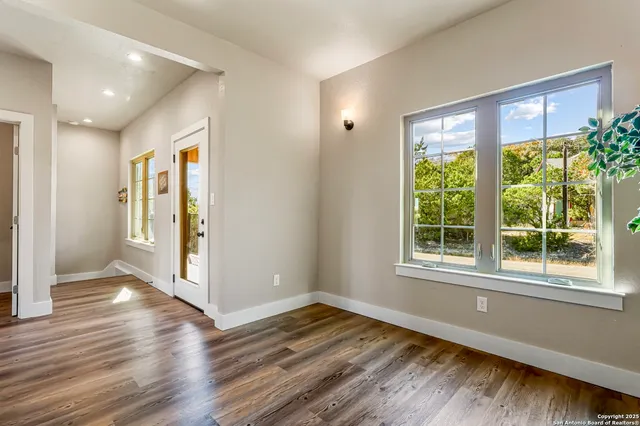 a view of an empty room with wooden floor and a window