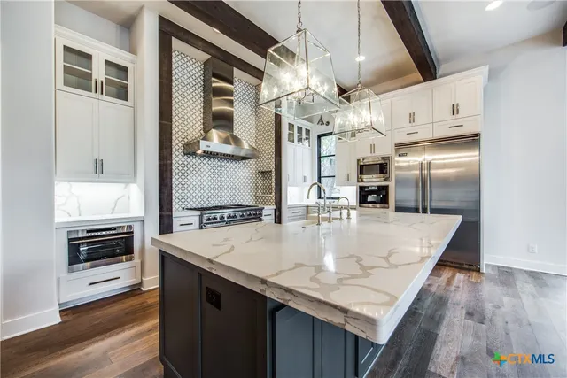 a kitchen with stainless steel appliances granite countertop a sink a oven and a refrigerator