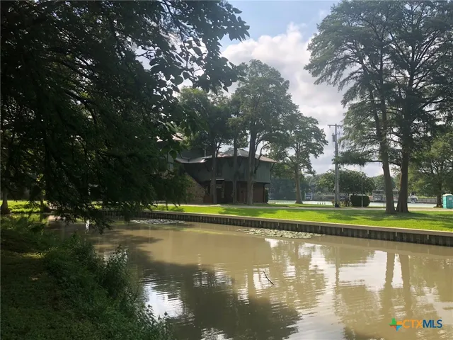 a view of a lake with a yard and large trees