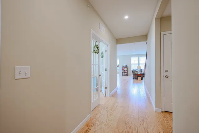 a view of a hallway with wooden floor and a living room
